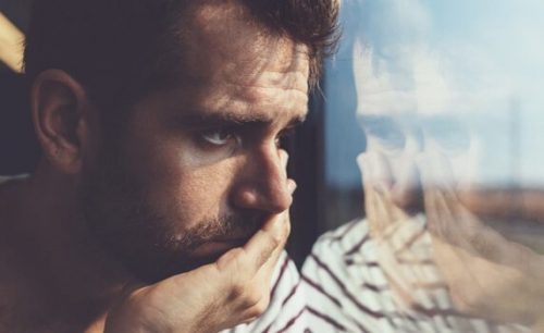 Man die droevig uit een raam kijken en het liefst zijn gebroken hart vermijden wil