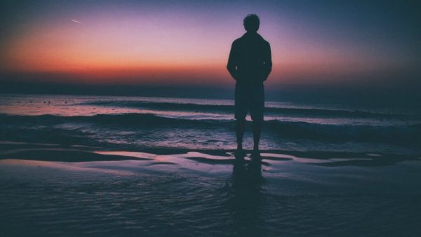 Man die op een strand staat, want een van de kenmerken van emotionele volwassenheid is nadenken over je toekomst