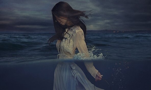 Vrouw die met haar kleding aan de zee in loopt, want woede is giftig