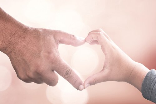 Hand van een oudere man die samen met de hand van een kind een hartje vormt