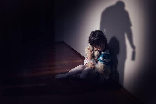 Kind met een teddybeer in de schaduw van zijn vader