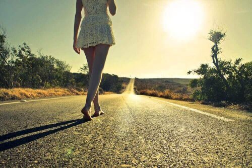 Meisje dat op haar blote voeten over een weg loopt