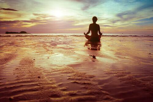 Persoon mediteert op het strand