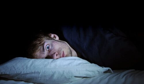 Man ligt met open ogen in bed