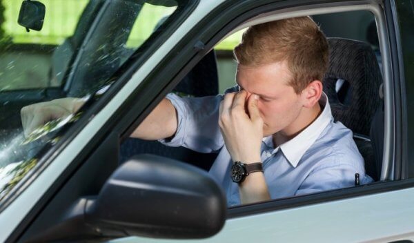 Man wrijft in zijn ogen achter het stuur van zijn auto