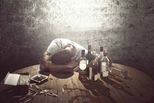 Dronken man omringd door flessen alcohol