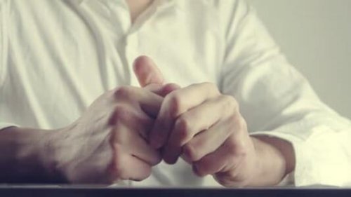 Man friemelt met zijn handen