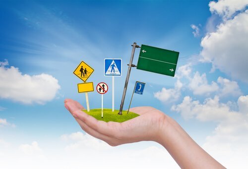 Een hand houdt verkeersborden vast