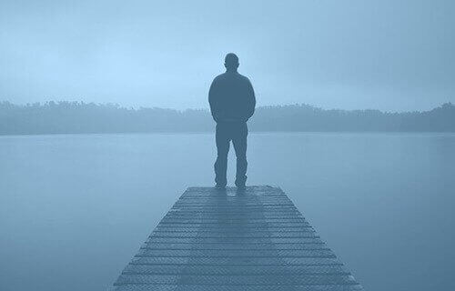 Man staat op pier in de mist