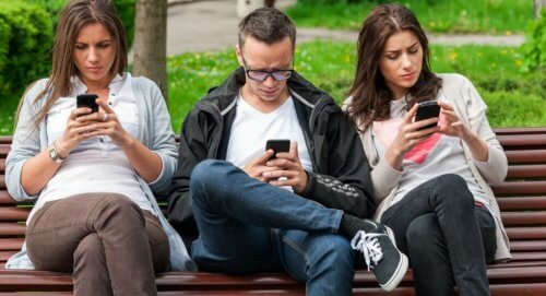 Groep mensen op een bankje kijken naar hun telefoons