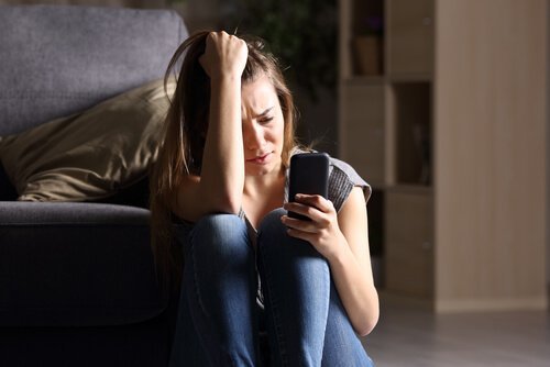 Vrouw kijkt bezorgd naar telefoon in haar hand