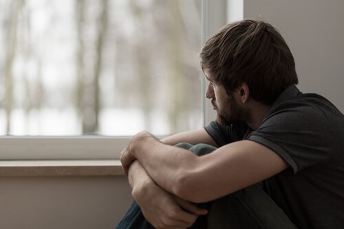Man met emotioneel leed kijkt uit het raam