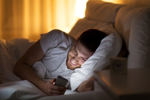 Man ligt in bed met zijn telefoon