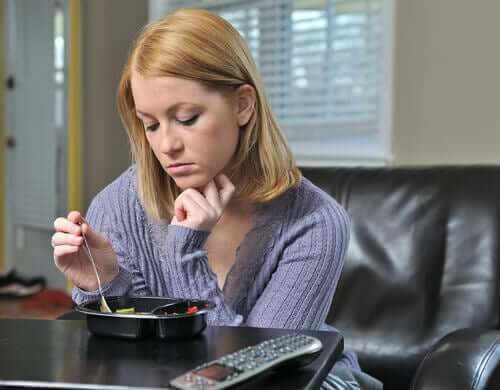 Eenzame vrouw zit aan tafel te eten