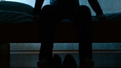 Man zit op bed in het donker