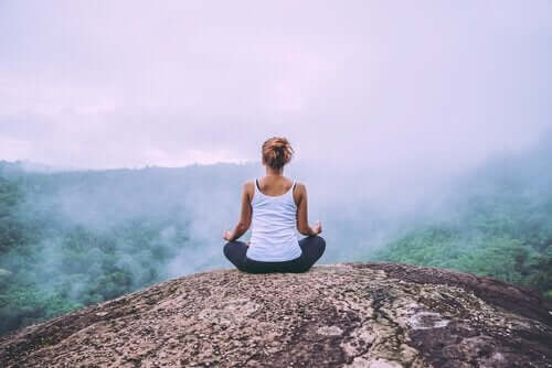 Vrouw mediteert op de top van een berg