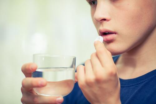 Tiener slikt pil met een glas water