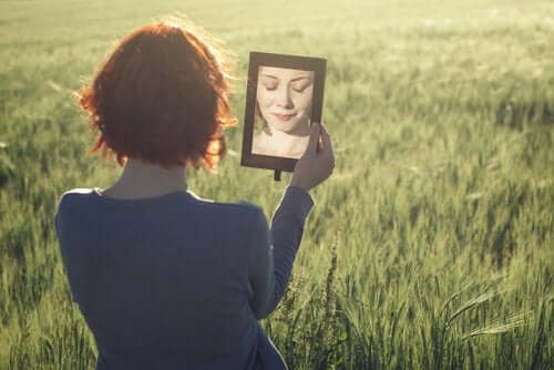 Een vrouw in een veld kijkt in een spiegel 