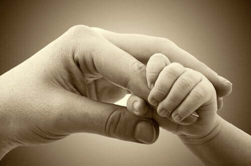 Een moeder houdt het handje van een baby vast