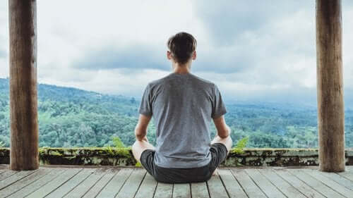 Een man mediteert en kijkt uit over bergen