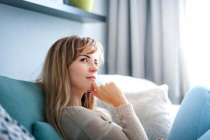 Een vrouw zit op de bank en denkt na