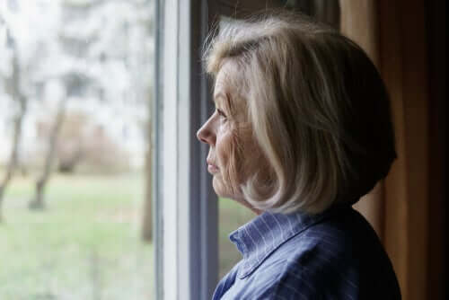 Een oudere vrouw kijkt uit het raam