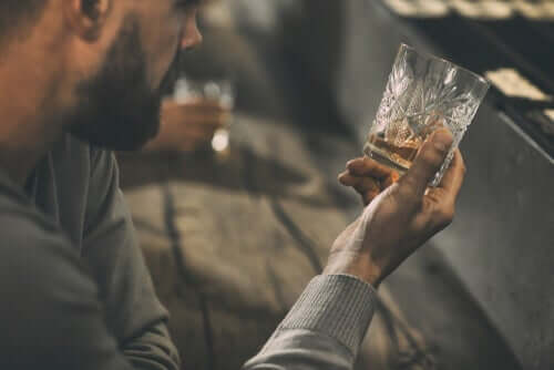 Een man kijkt naar een bijna leeg glas alcohol