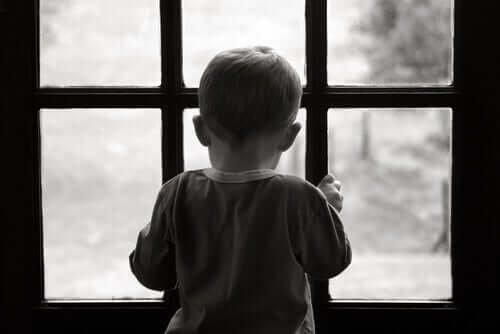 Een jongetje kijkt uit een raam