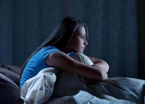 Een vrouw zit in het donker rechtop in bed