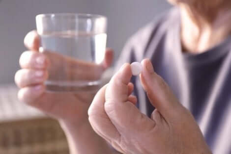 Een man neemt een pil in met een glas water