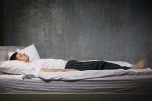 Een man ligt in bed met zijn ogen dicht