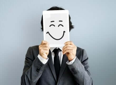 Een man houdt een vel papier met een lachend gezicht voor zijn eigen gezicht