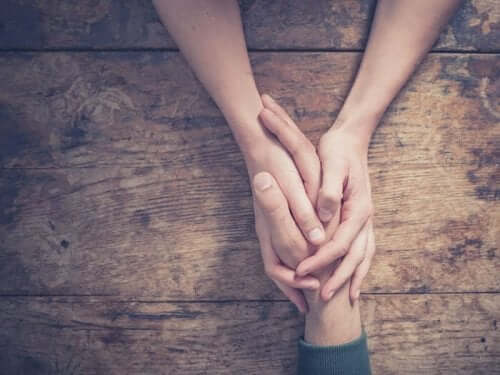 Een vrouw houdt de hand van een man vast boven een tafel