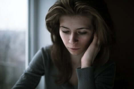 Een vrouw leunt op haar hand en kijkt naar beneden