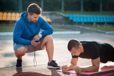 Een trainer kijkt toe hoe een sporter zich opdrukt