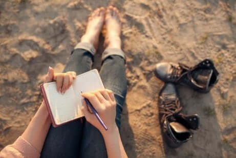 Een vrouw schrijft in een notitieboek op het strand