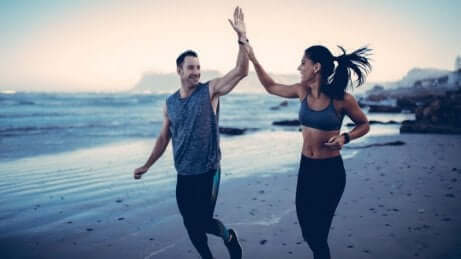 Een man en een vrouw geven elkaar een high five op het strand