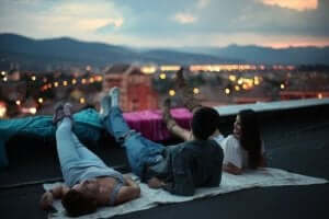 Drie vrienden zitten op de rand van een dak van een hoog gebouw