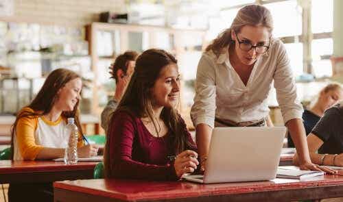 Een studente zit achter haar laptop terwijl een docente met haar meekijkt