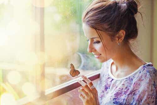 Een vrouw kijkt naar een vlinder die op het raam zit
