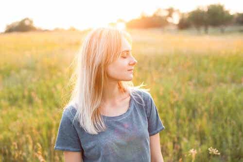 Een vrouw staat in een grasveld met haar ogen dicht