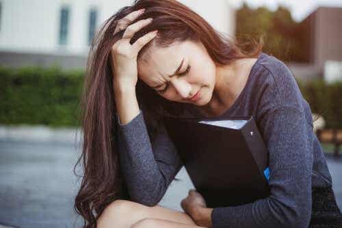 Een vrouw zit met haar hand in haar haar en kijkt bezorgd