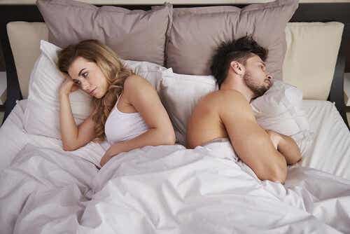 Een man en een vrouw liggen in bed met de ruggen naar elkaar toe