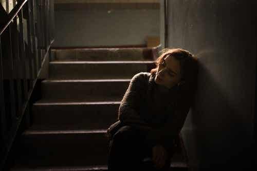 Een verdrietige vrouw leunt tegen de muur in een trappenhuis