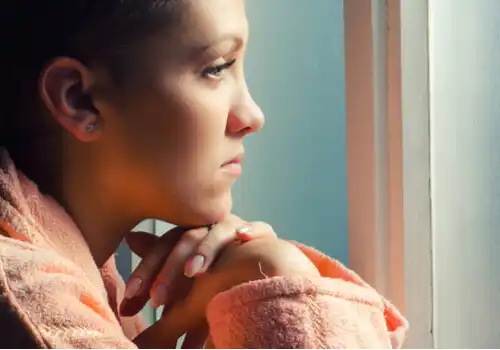 Vrouw met kanker kijkt uit het raam